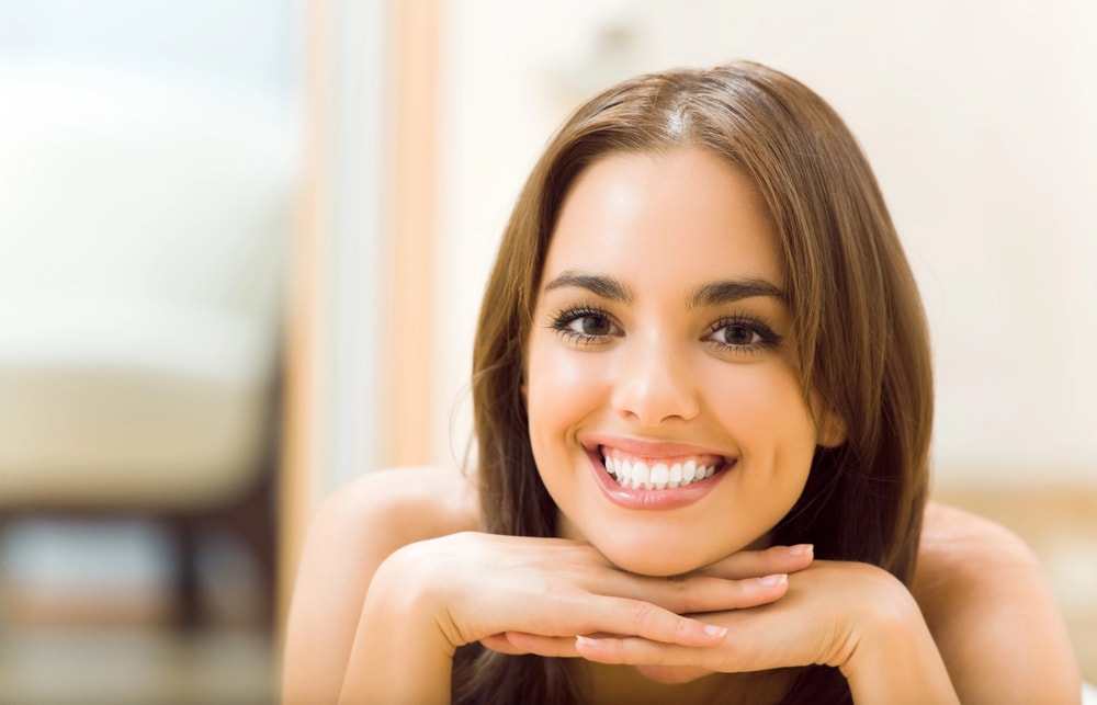 Close-up of a woman's smile, showcasing dental bridge and perfectly aligned teeth.